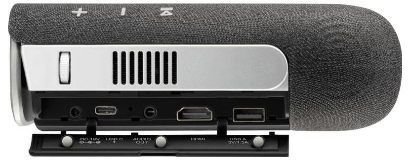 Grey portable projector with foldable cover. Visible connections: HDMI, USB, audio and power supply. Control buttons on top.