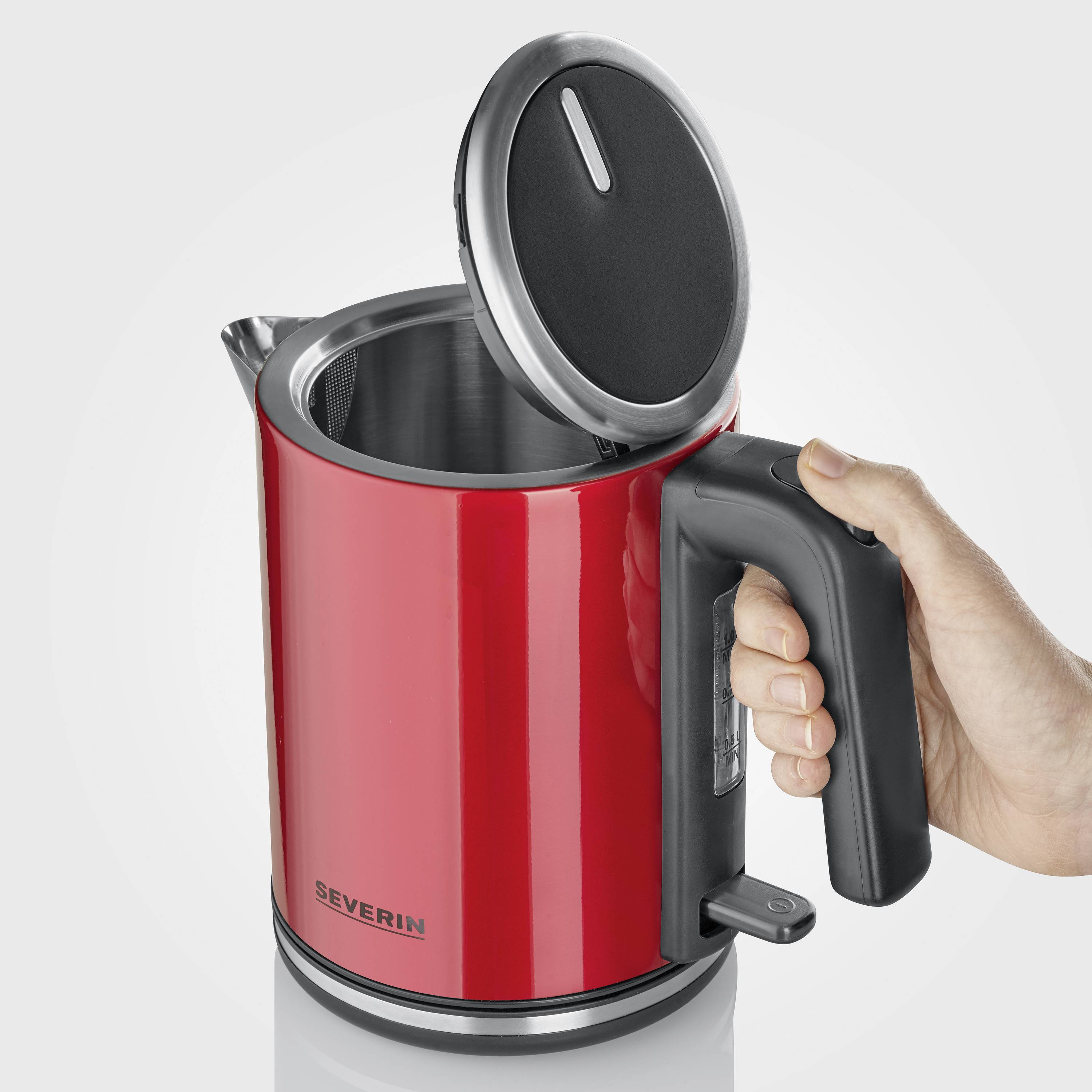 Red stainless steel kettle with an open lid and visible strainer, being held by a hand on the black handle.