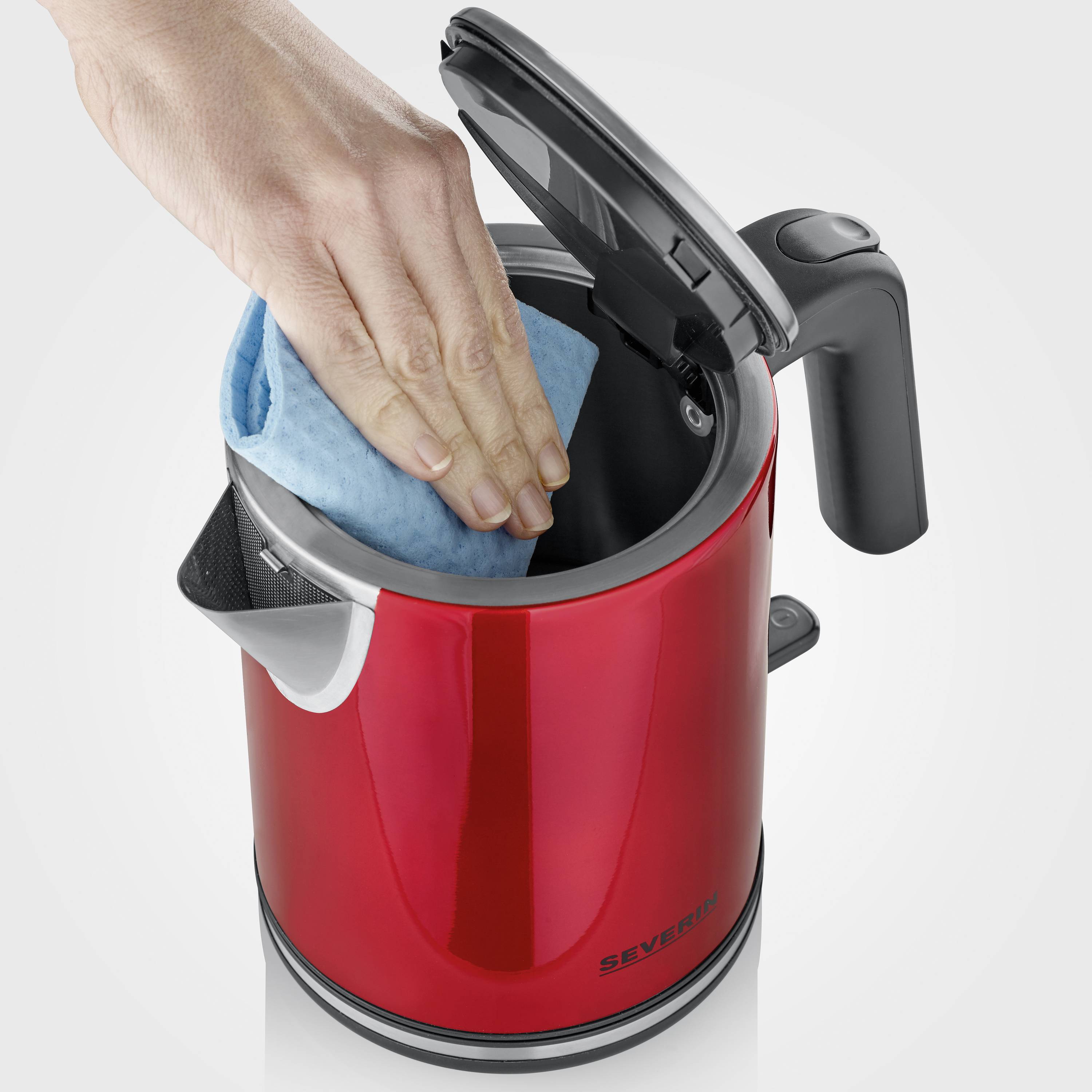 A hand reaches into an opened red electric kettle with a blue cloth.