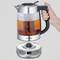 A hand is holding a transparent kettle with a black handle. The kettle is situated on a silver base with a digital display.