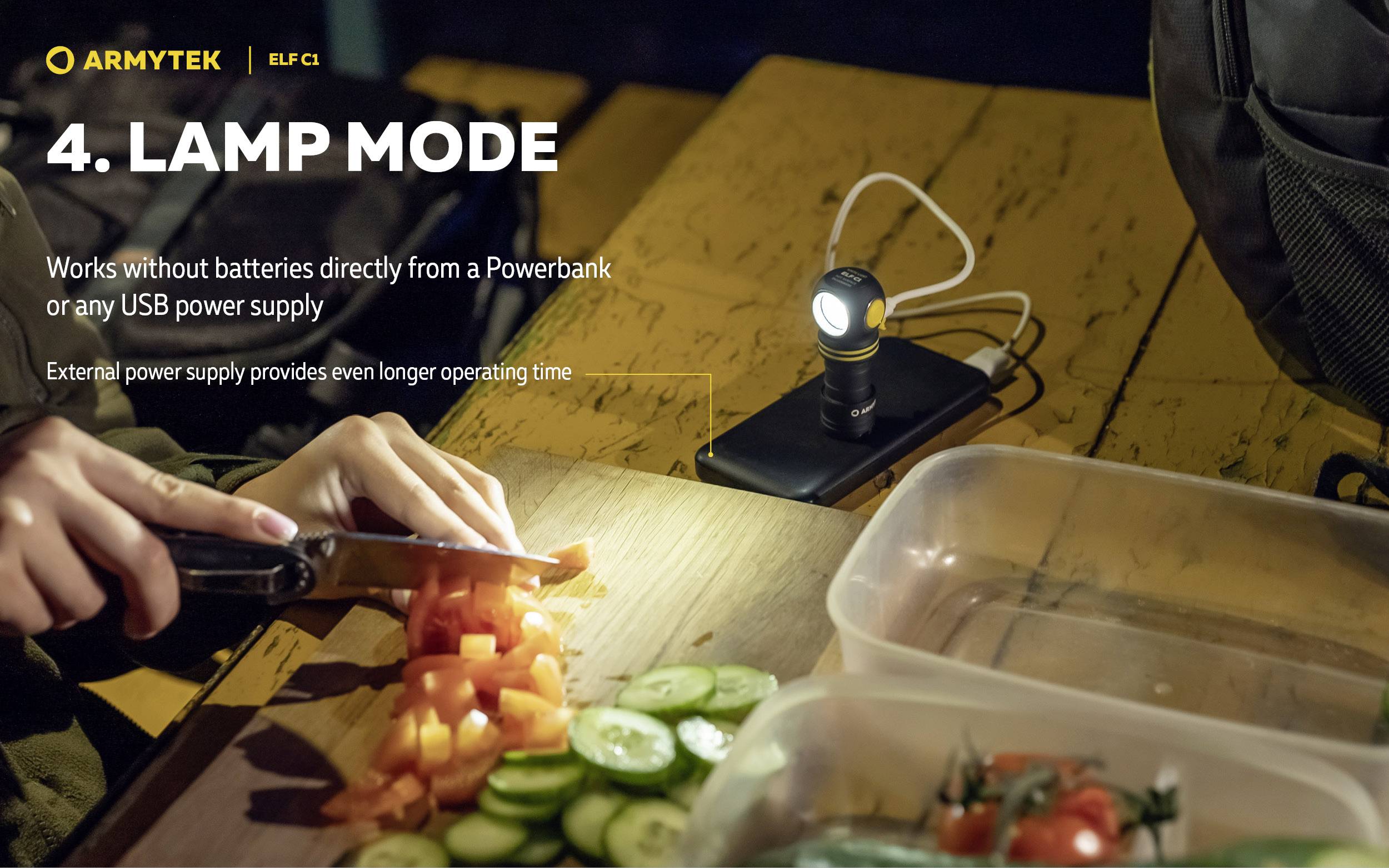 A person is chopping vegetables on an outdoor table at night, illuminated by a small lamp powered by a portable power bank.