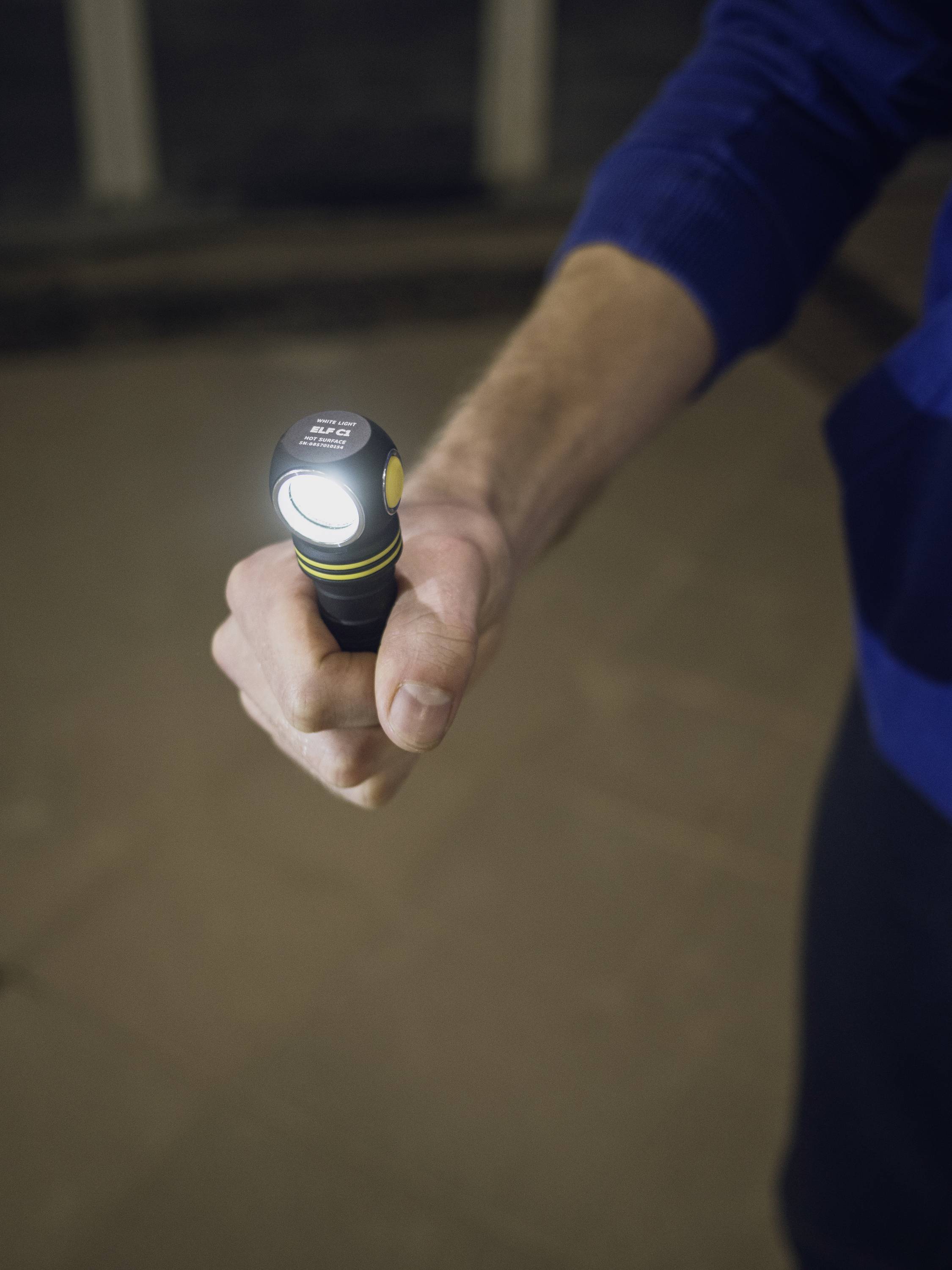A person is holding a switched-on torch in their hand, shining it forward. The surroundings are dark.