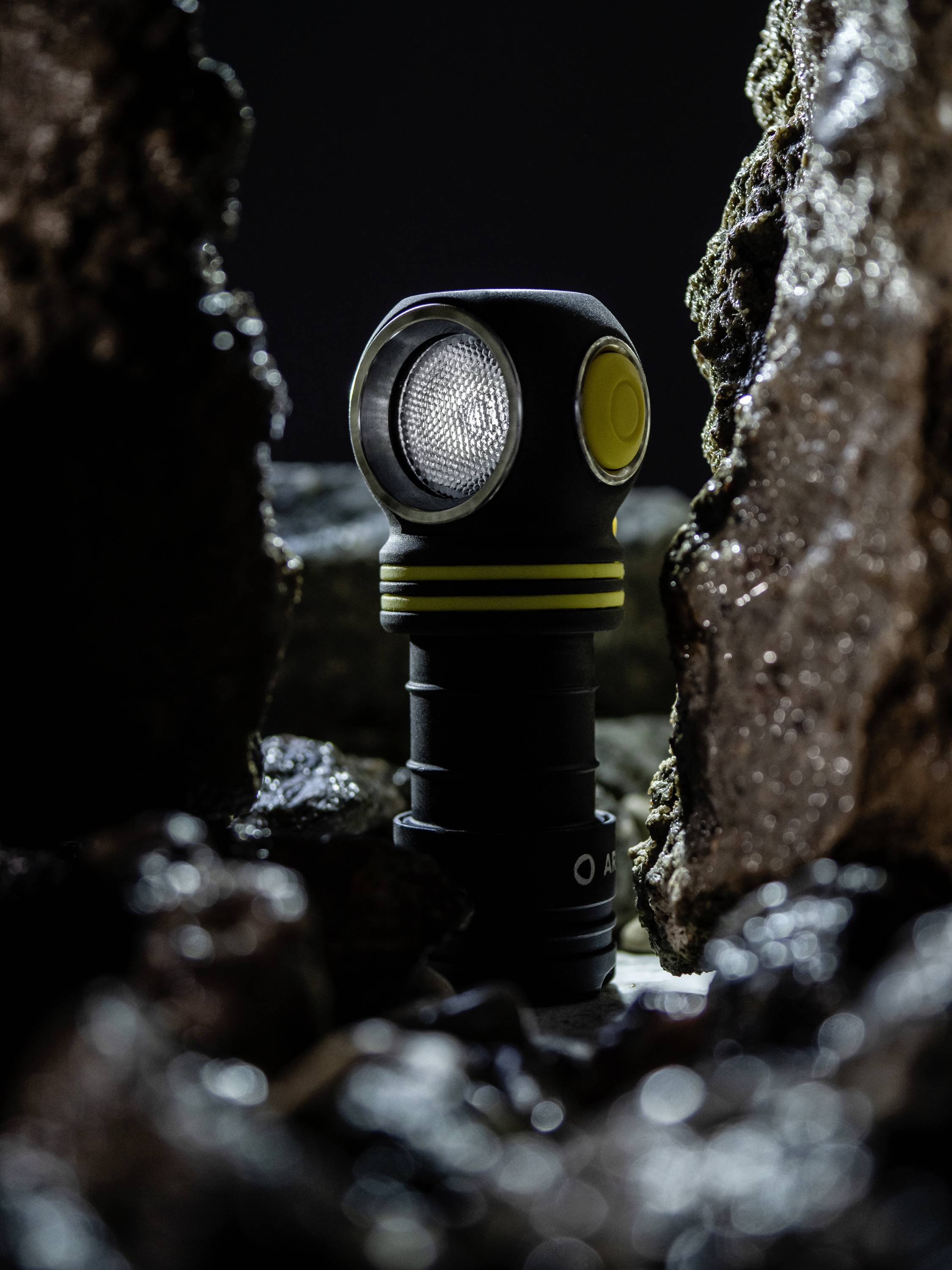 Torch in a cave environment between rocks, weak light emphasising the textured surface and robust design.