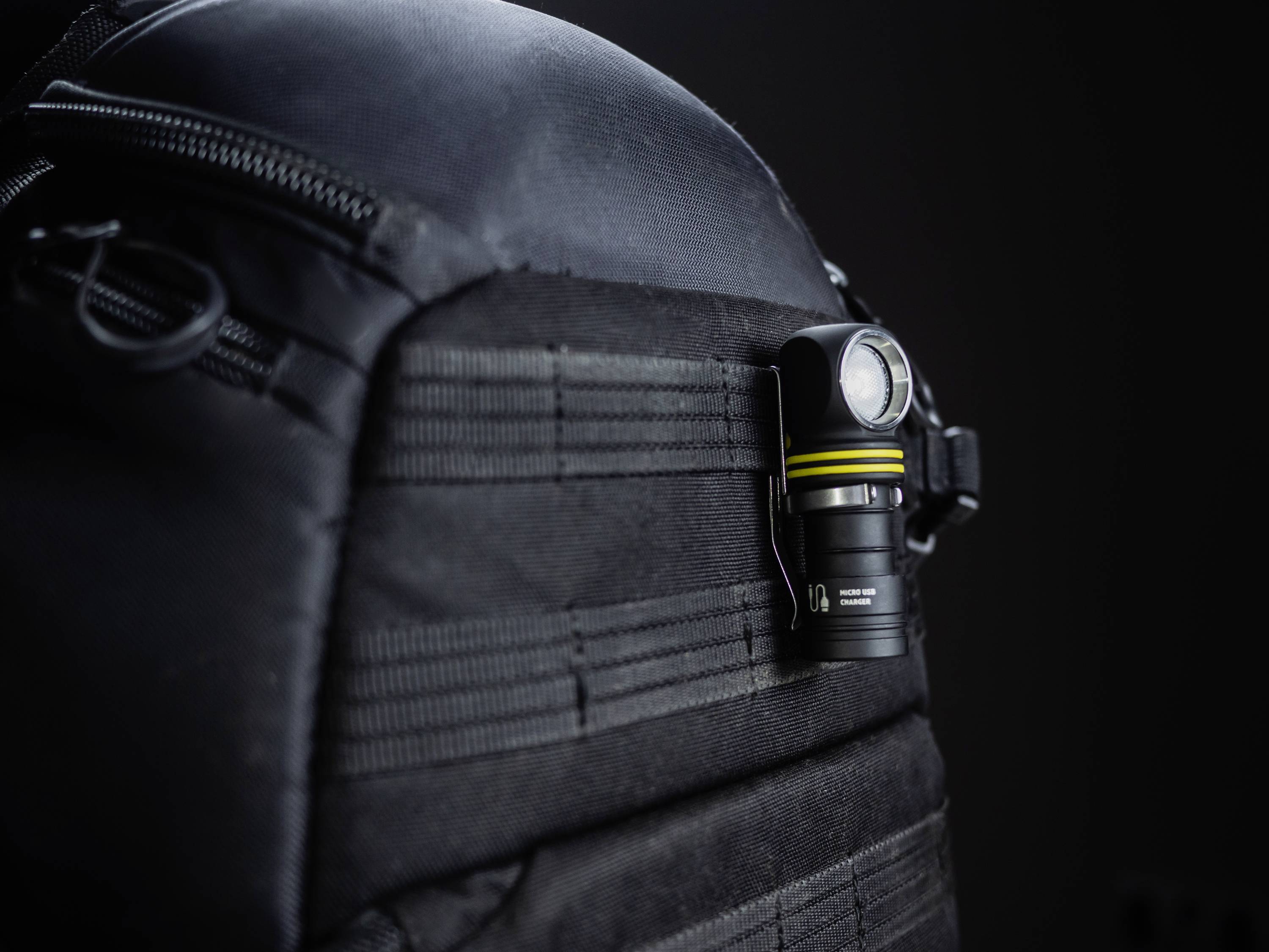 Black rucksack with a small torch attached to the side. The scene suggests equipment for outdoor activities.