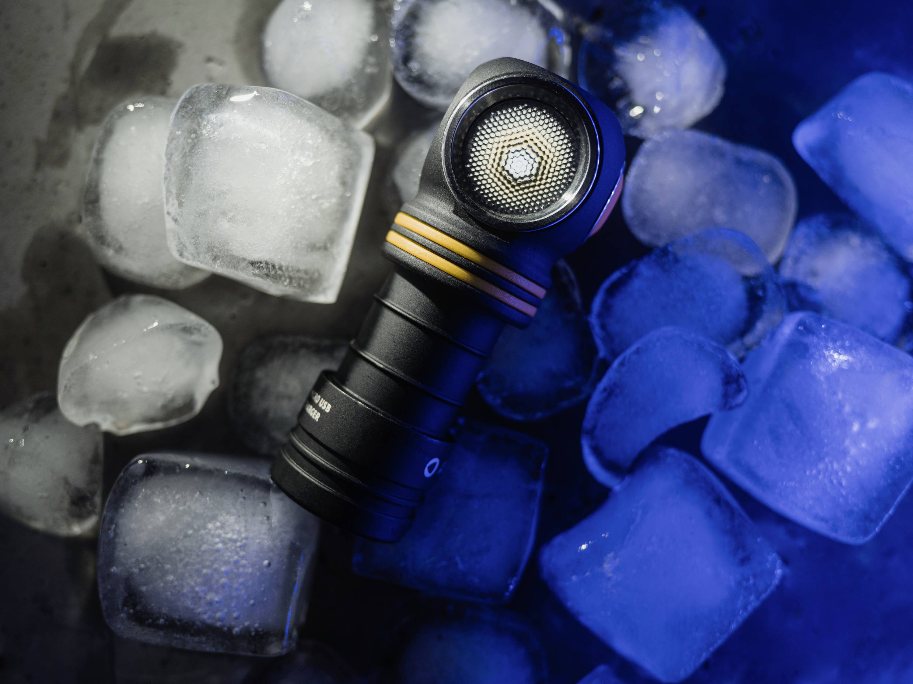 Torch lies on ice cubes, illuminated in blue light.