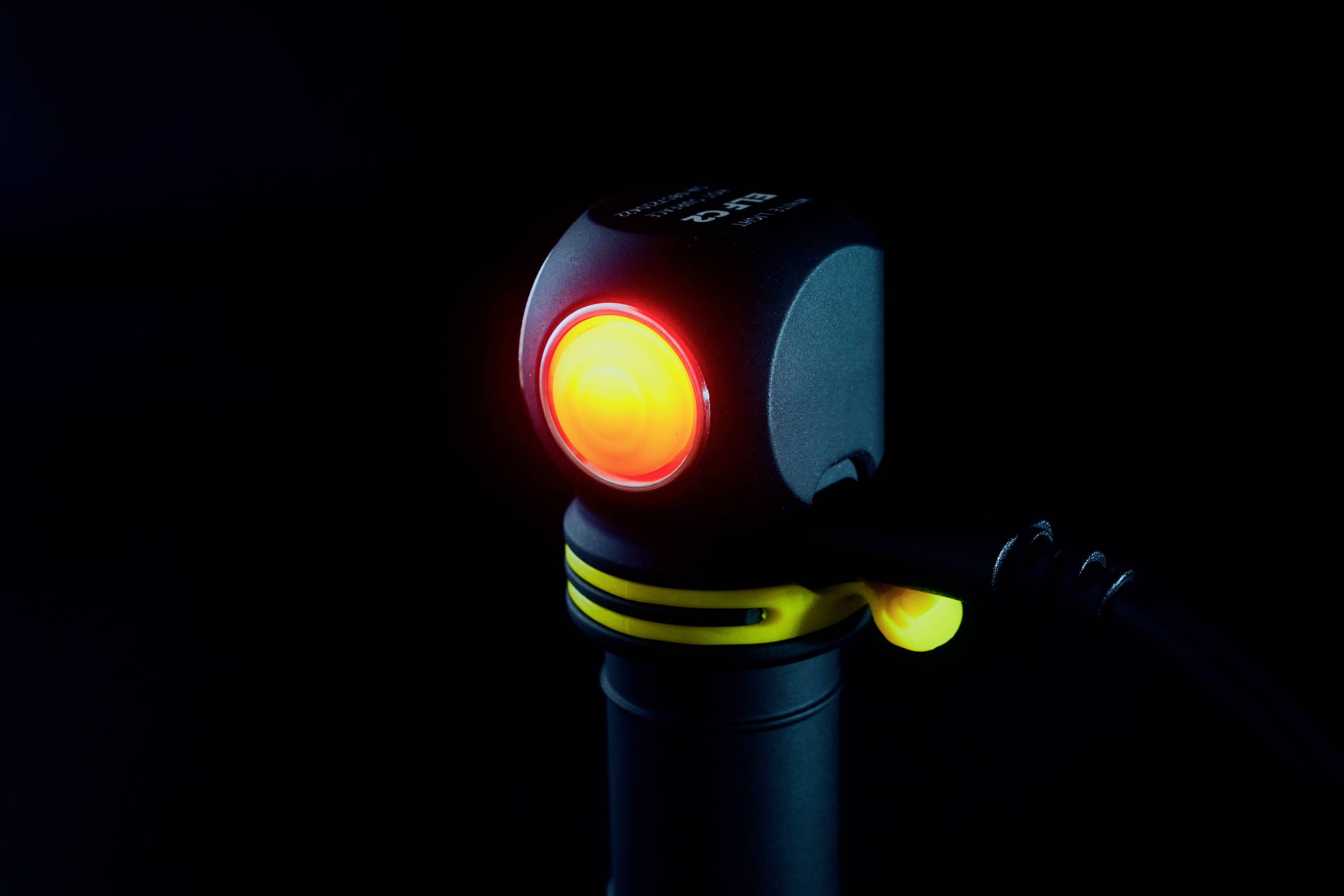 A small, luminous device with a red light on a black background indicates that it is activated or in operation.