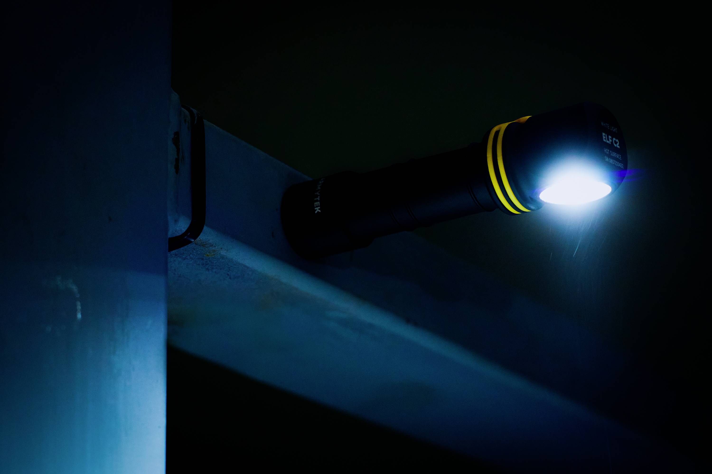 A torch hangs from a metal beam and shines brightly in a dark room.