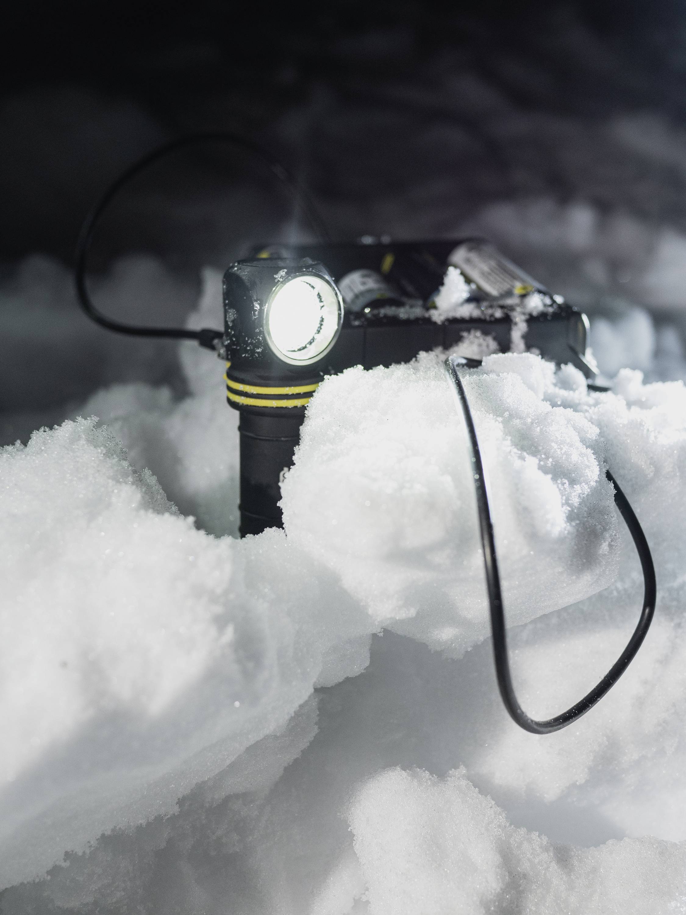 Torch in the snow; shining brightly in a dark environment, surrounded by cable.