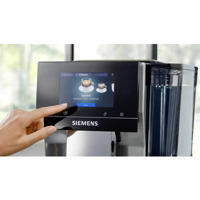 A hand is using a Siemens fully automatic coffee machine display to select an espresso. The display shows options for coffee types.