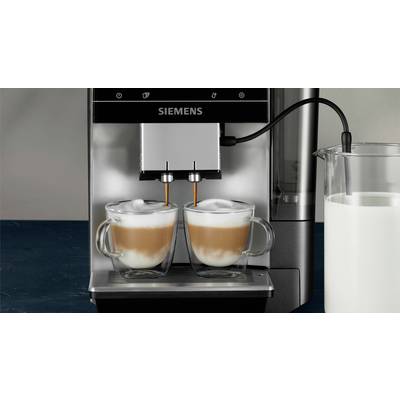Two cappuccinos are being filled side by side from a Siemens fully automatic coffee machine into handled glasses. A milk container is standing on the right.