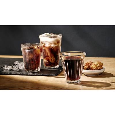 Three glasses of cold drinks, presumably iced coffee, on a table. Beside them, a small bowl of snacks.