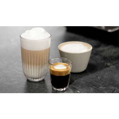 Three different coffee types: A glass of latte macchiato, a cup of cappuccino, and an espresso in a small glass on a dark table.
