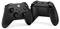 Two black gaming controllers, one shown from the front and one from the back. Both have buttons and joysticks.