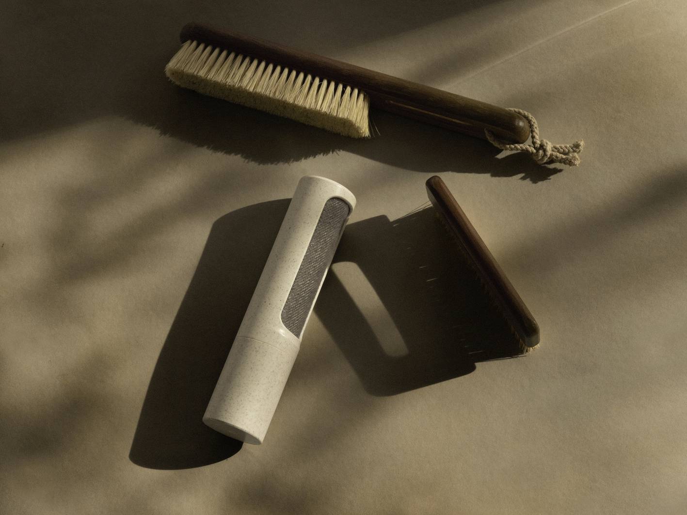 Three cleaning brushes made of wood and natural materials lie on a brown surface in soft light.