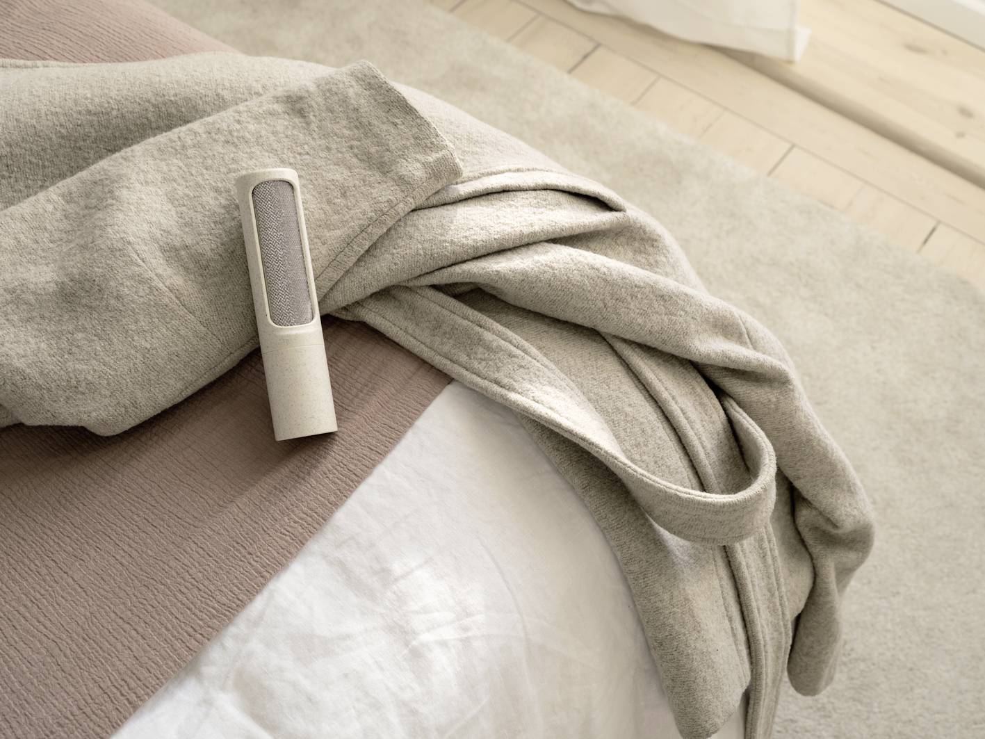 A speaker is resting on a soft, beige fabric draped over part of a bed.