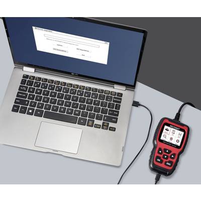 A laptop is connected to a diagnostic tool via a cable. A software interface is displayed on the laptop screen.