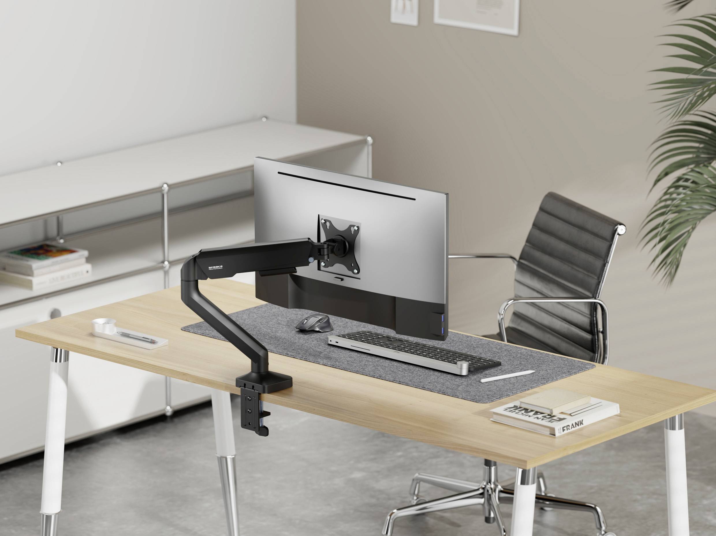Modern desk with a computer monitor on an adjustable arm, a chair and an organiser. Office or work environment.
