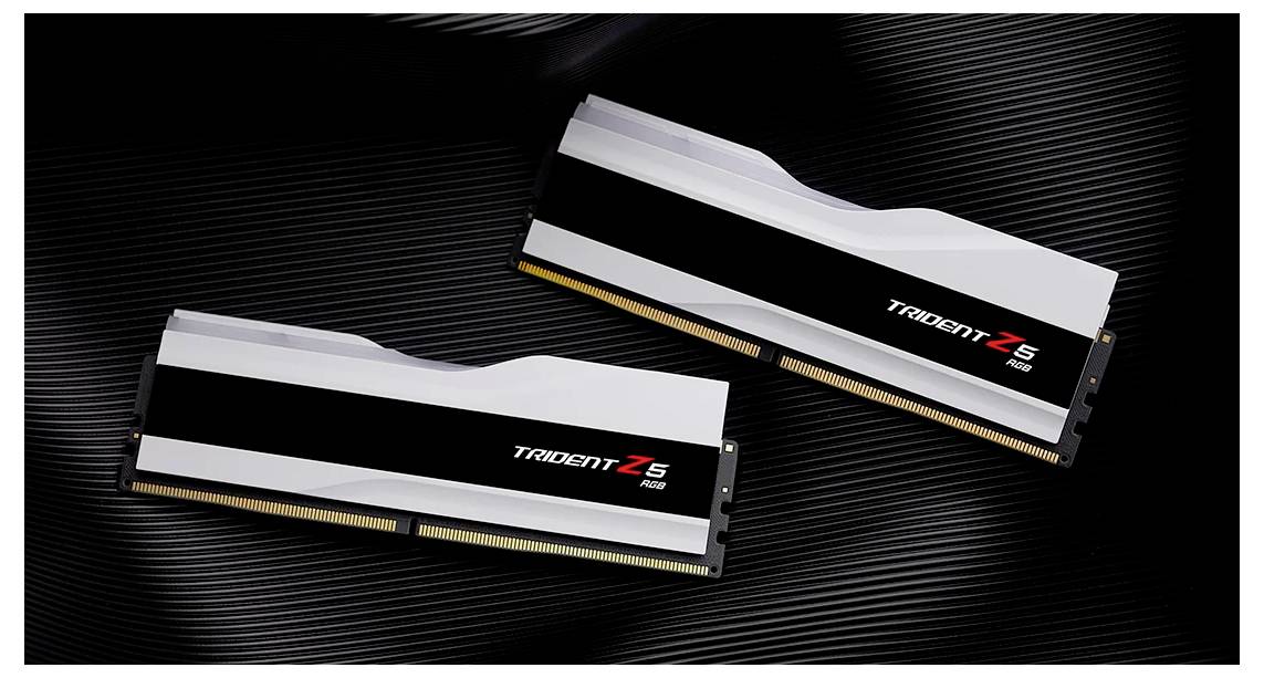 Two RAM modules of the 'Trident Z5 RGB' series are lying on a ribbed surface. They are black and white with red accents.