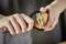 A person is peeling a potato with a black vegetable peeler.