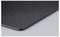 The corner of a black mousepad with rounded edges on a smooth surface.