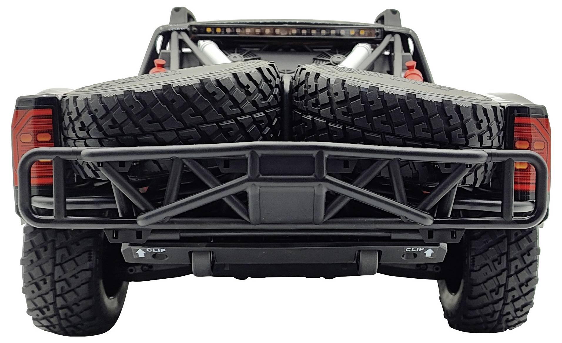 A vehicle with two large spare tyres on the load bed, photographed from the rear. The tyres are securely fastened.