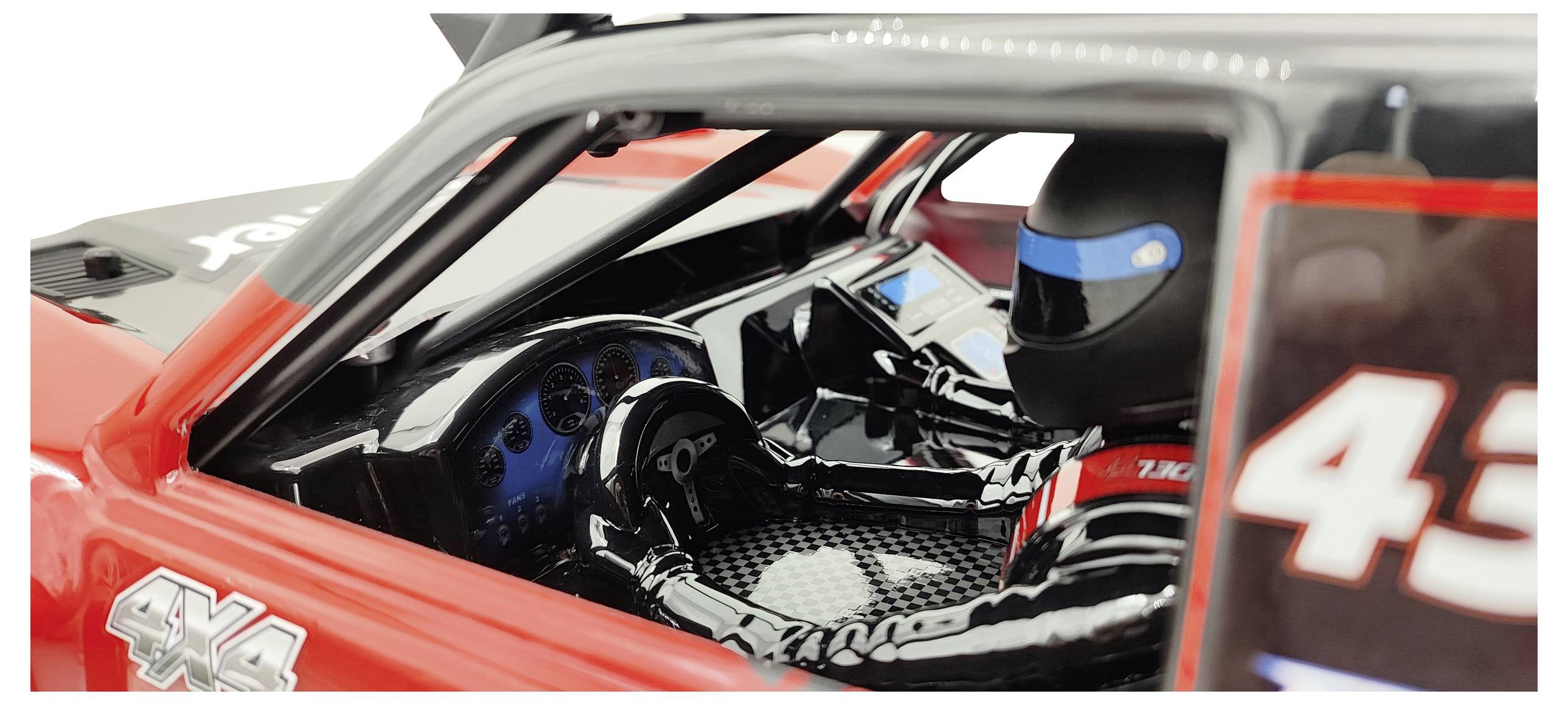 A close-up of the interior of a model car with a tiny helmet and steering wheel. The car shows red and black details.