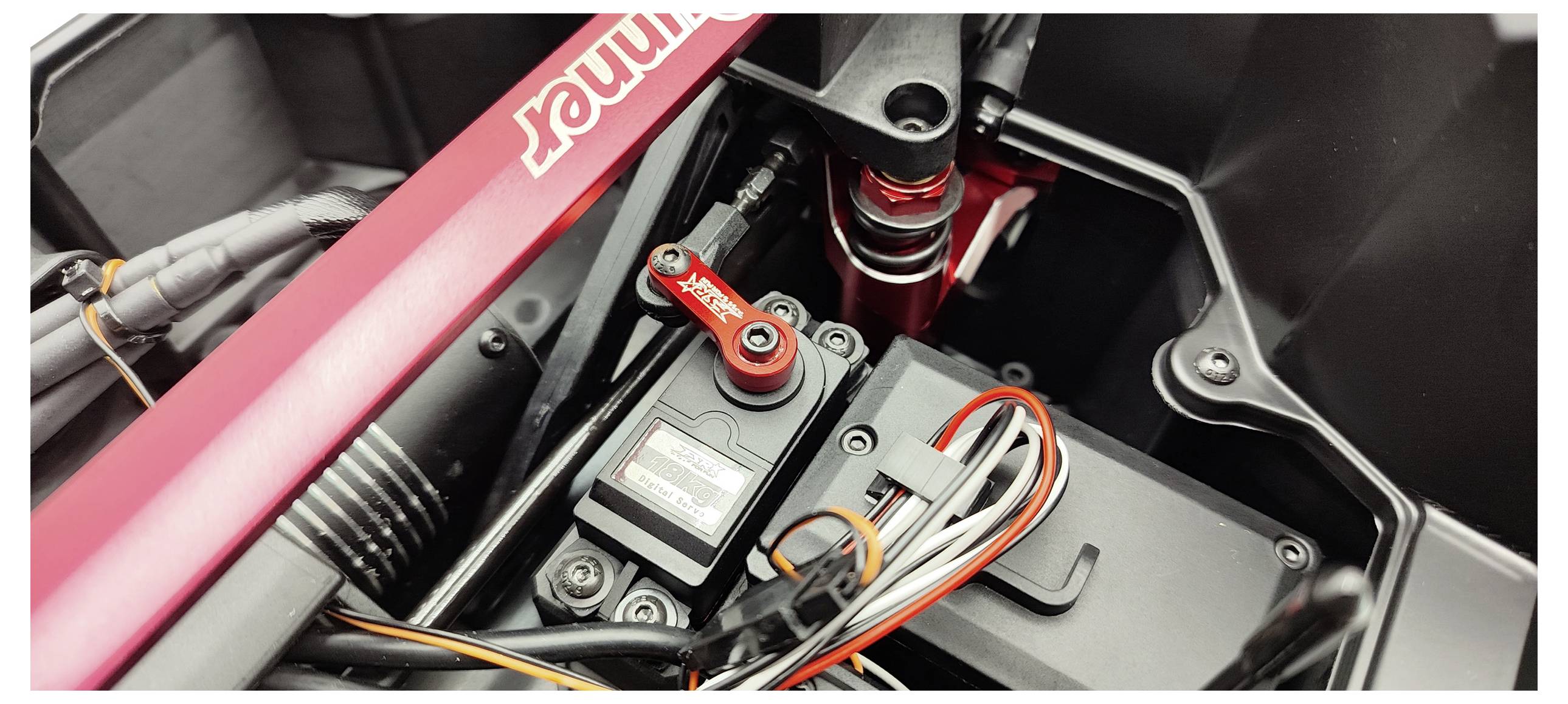 A close-up of an electronics and wiring system inside a technical device, featuring a servo and various connections.