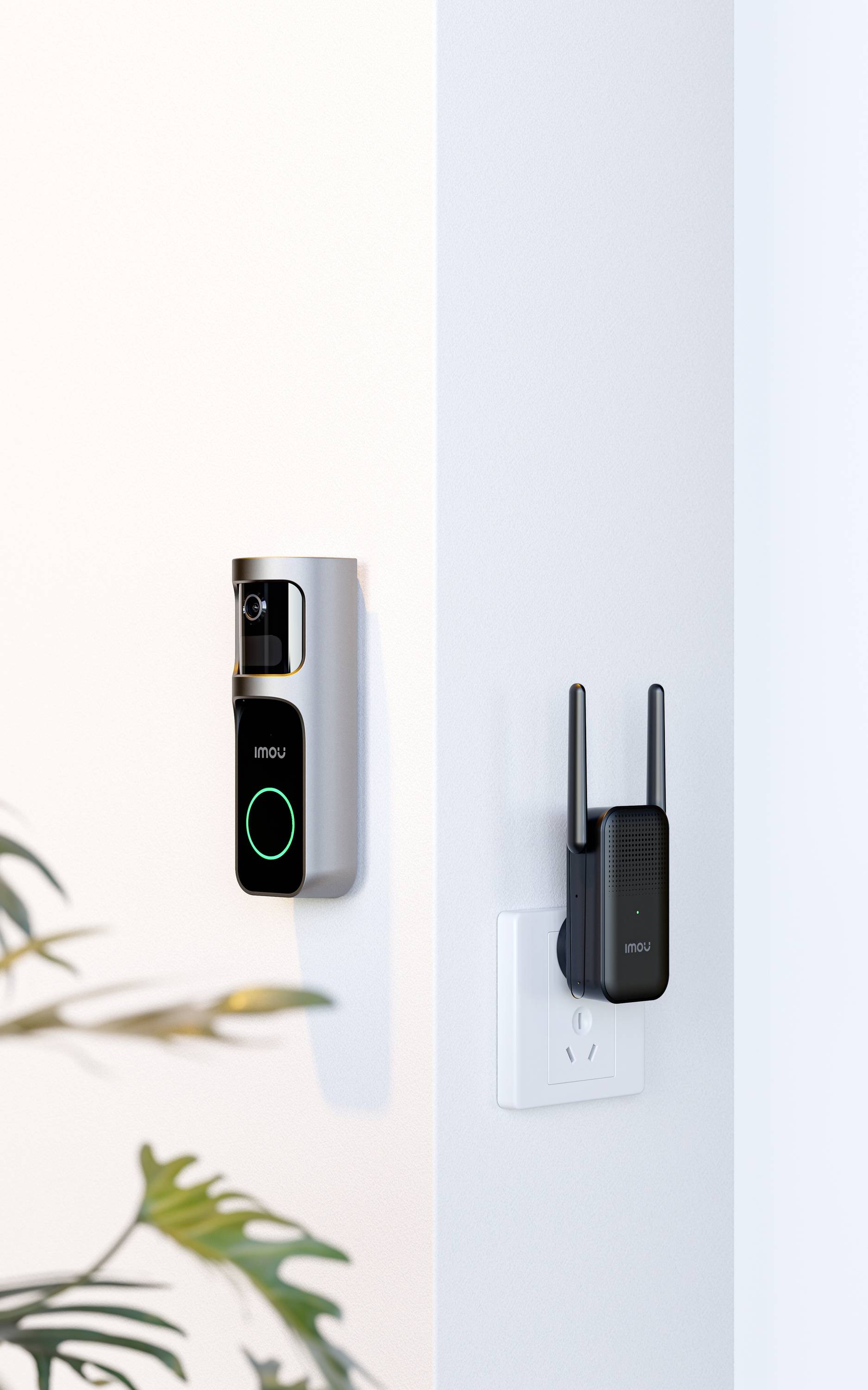 A smart doorbell with a camera and a WiFi extender are mounted on a white wall. Some plants are visible on the left side of the image.