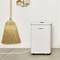 A broom is leaning against the wall next to a Bosch air purifier on a concrete floor. Both objects are situated in a bright room.