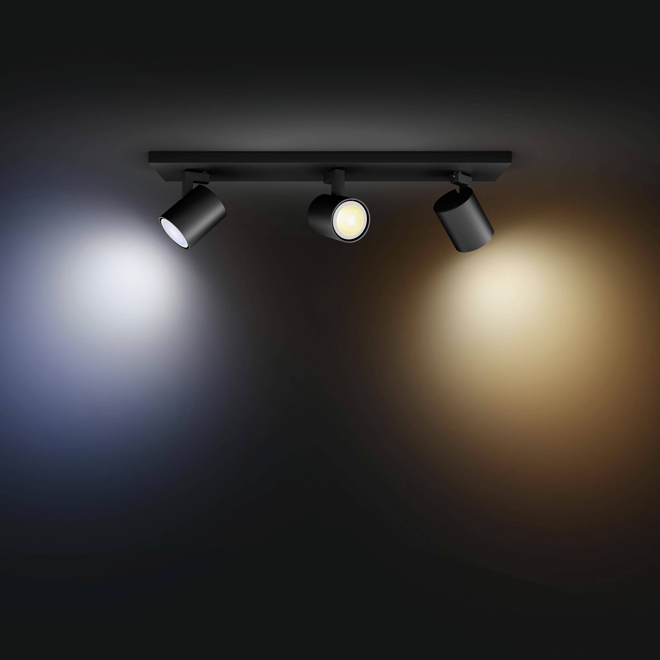 Three adjustable ceiling spotlights illuminate against a dark background in different light colours: neutral white, warm white, and cool white.