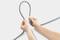 Two hands are holding a grey cable formed into a loop against a light background.