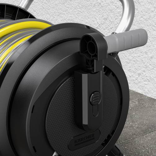 'Close-up of a black garden hose reel with a yellow hose. A grey concrete wall is in the background.'