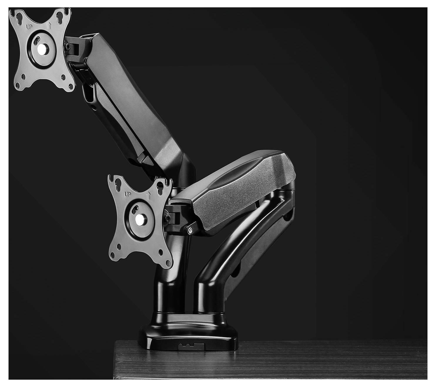 Metal dual monitor arm, mounted on a desk. The arms are height-adjustable and allow flexible screen positioning.