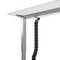 A height-adjustable desk with a cable management solution, where cables are neatly routed through a flexible guide beneath the desktop.