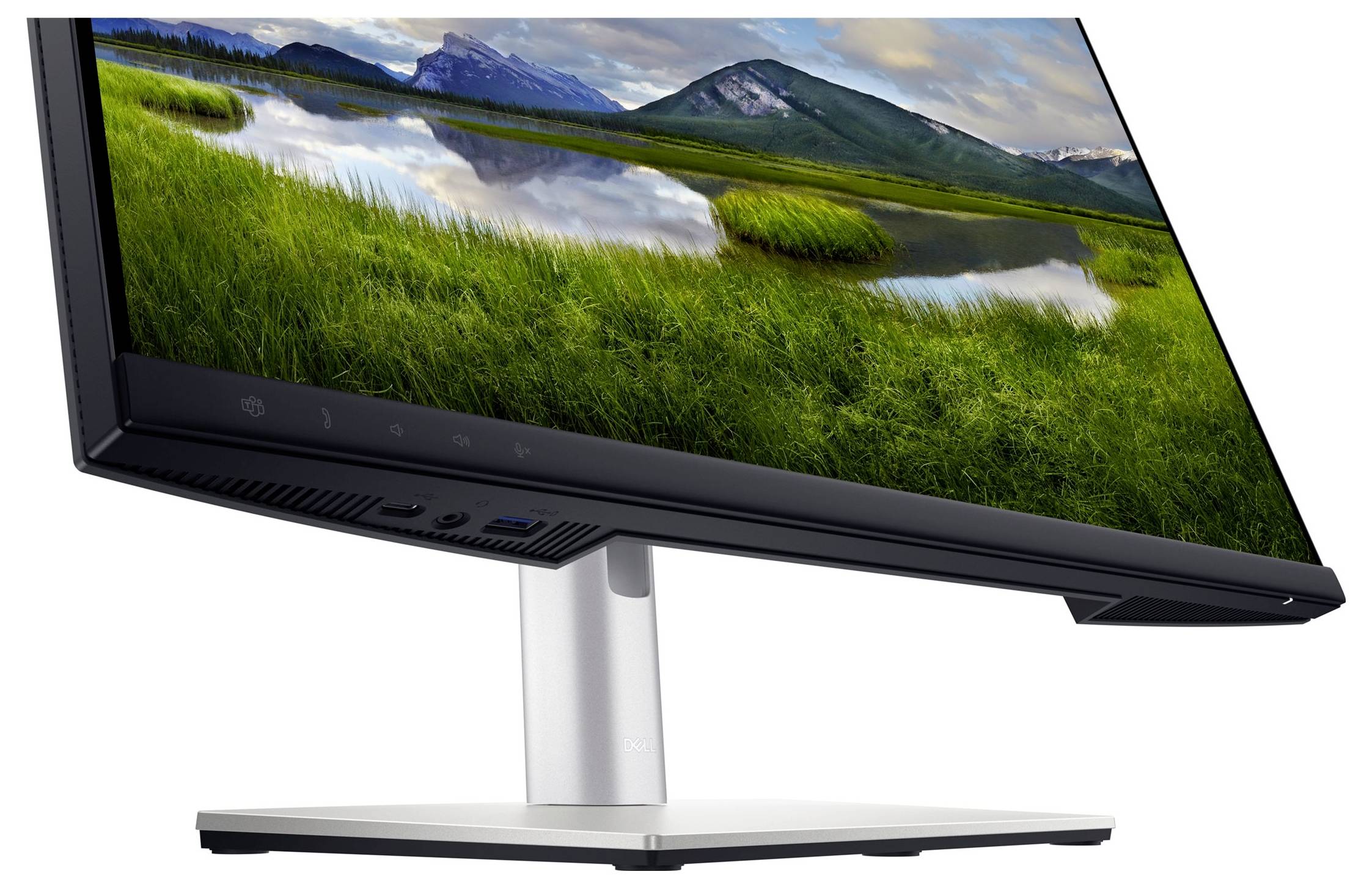 A monitor displays a landscape with green meadows and mountains in the background, reflecting in a tranquil lake.