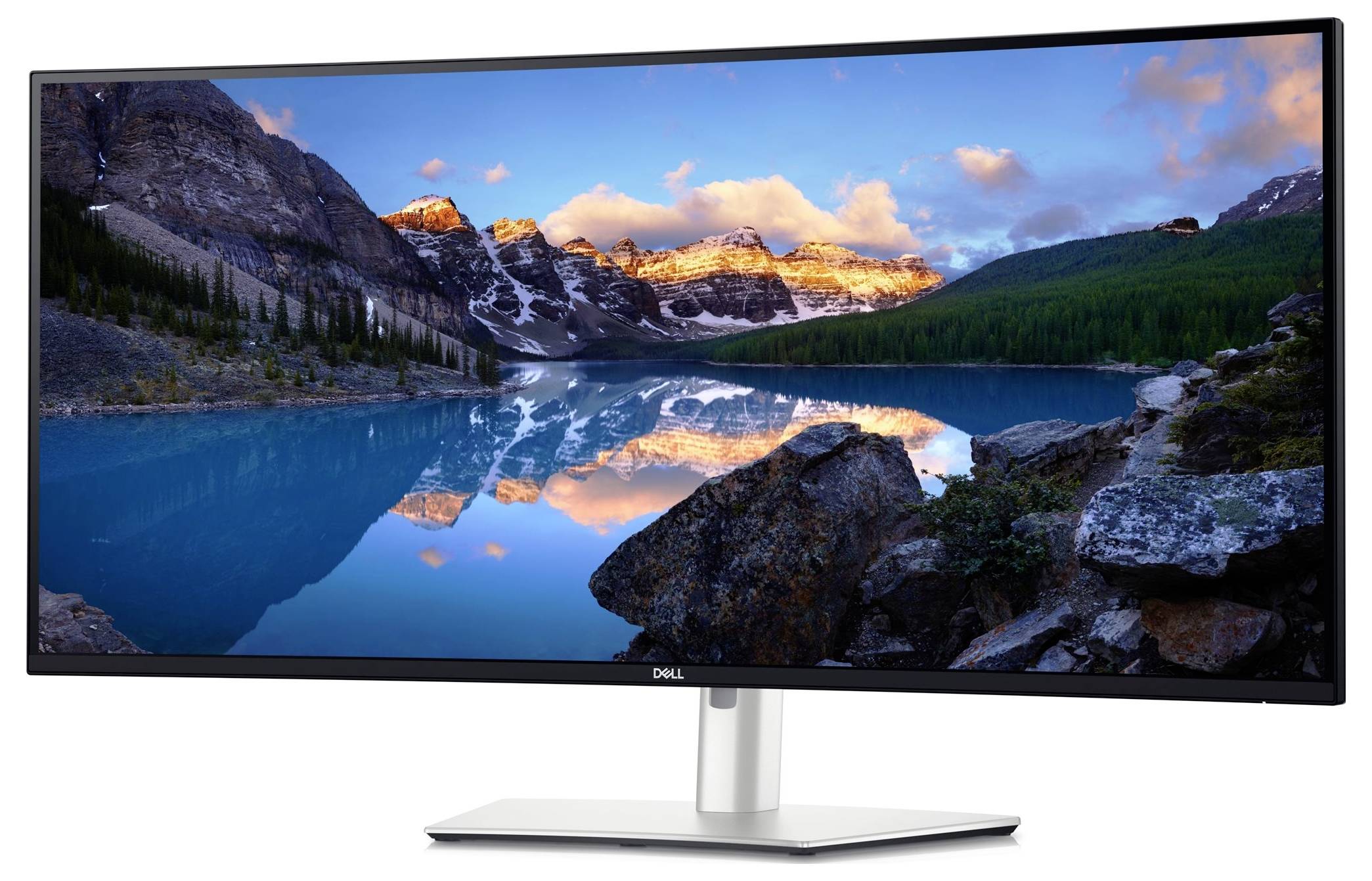 An ultra-wide Dell monitor displays an impressive natural landscape with mountains, a lake and clouds in the background.