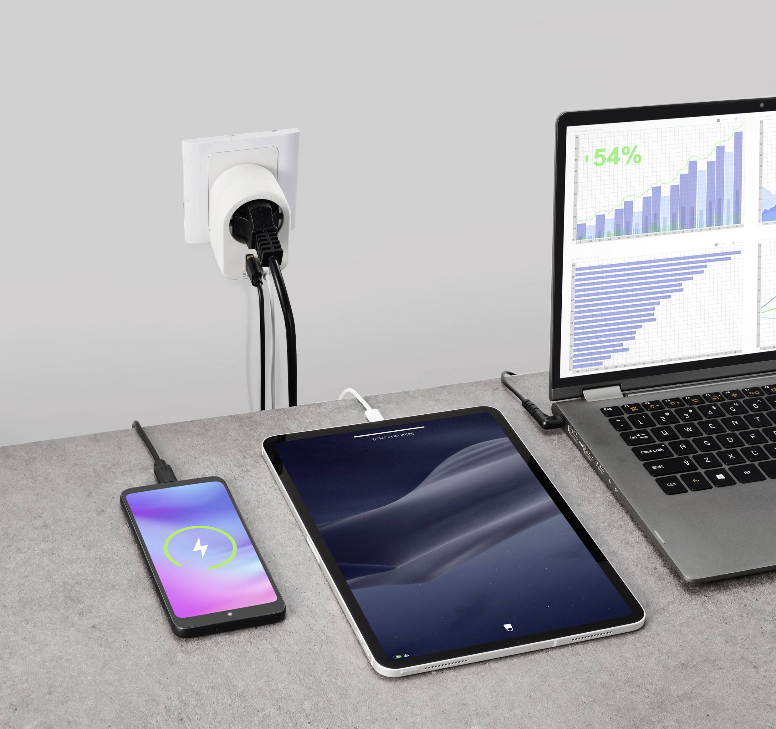 A laptop displays a diagram showing a 54% increase, alongside a tablet and smartphone charging at a power socket.
