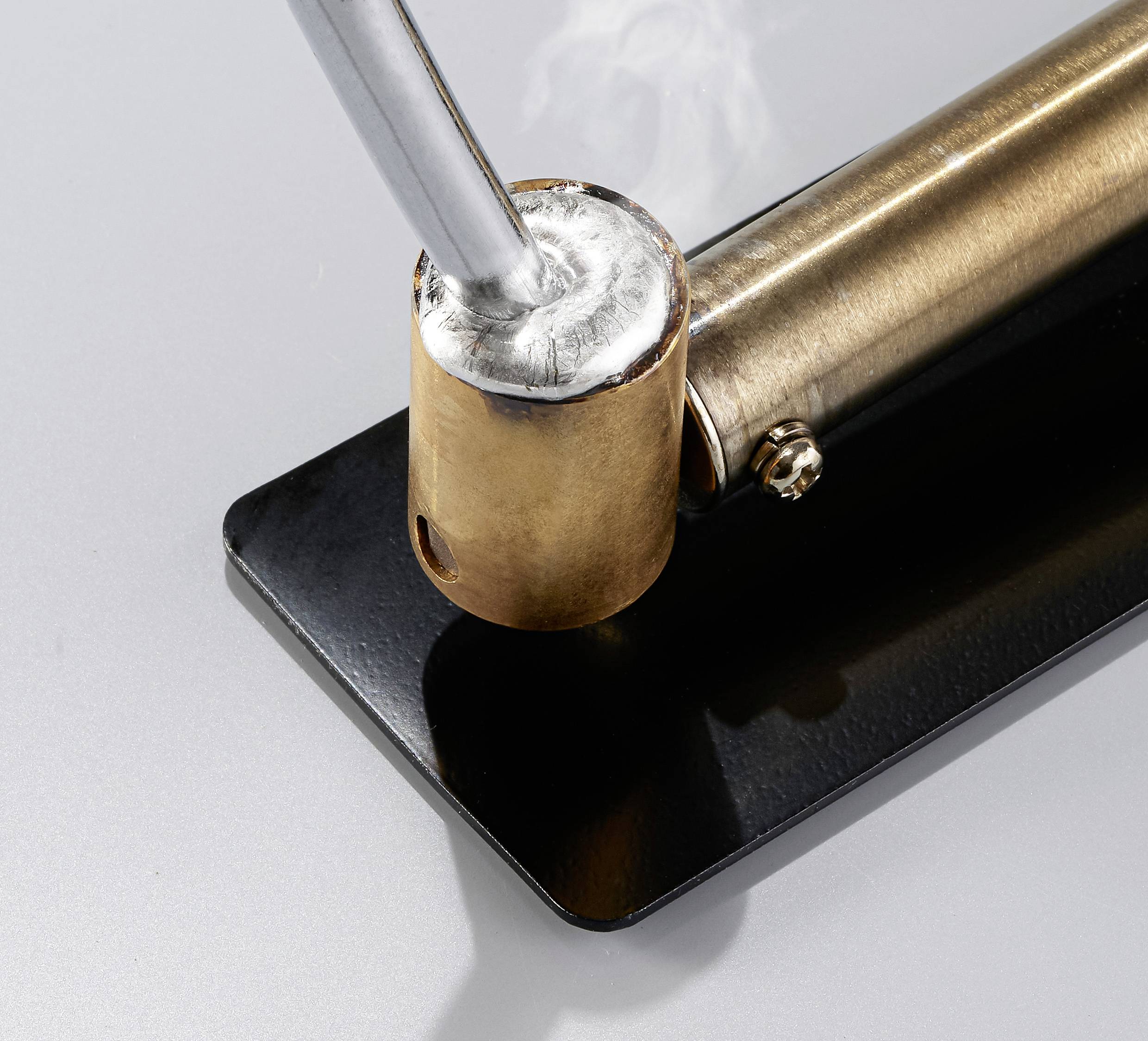 A closed tobacco pipe holder with a metal exterior and smoke rising from the mouthpiece.