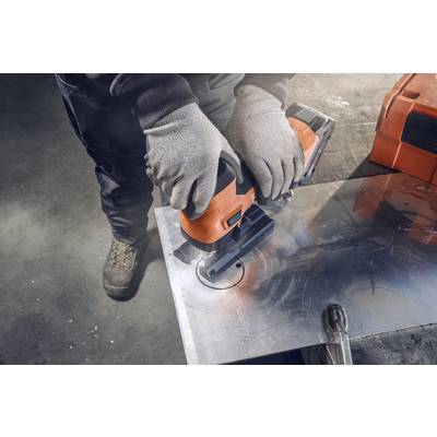 A person is cutting a round hole in a sheet of metal using a jigsaw. They are wearing protective gloves and boots.
