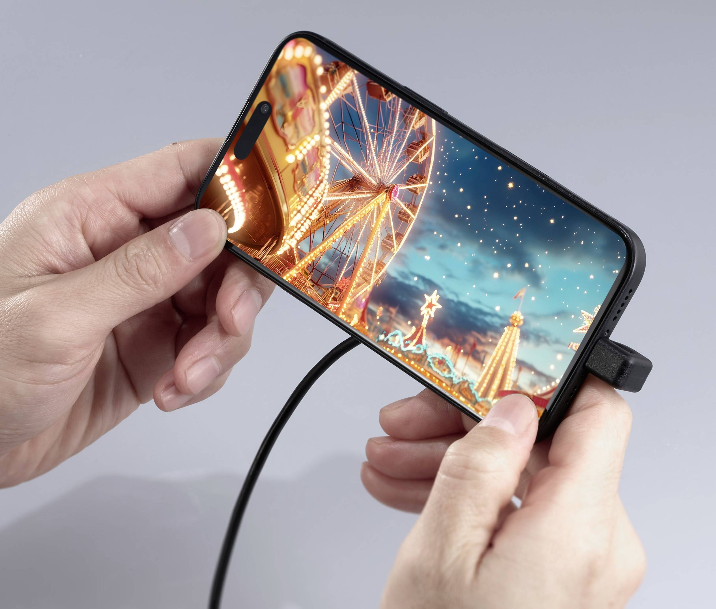 A person is holding a smartphone displaying a glowing Ferris wheel in an amusement park at night.