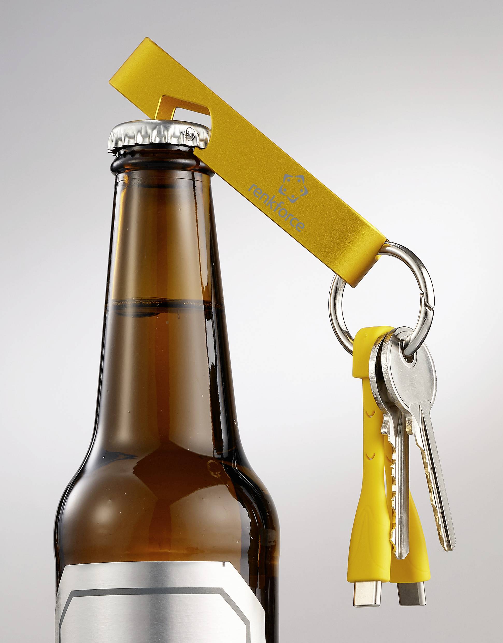 A yellow bottle opener is opening a beer bottle. Two keys are hanging from the opener.