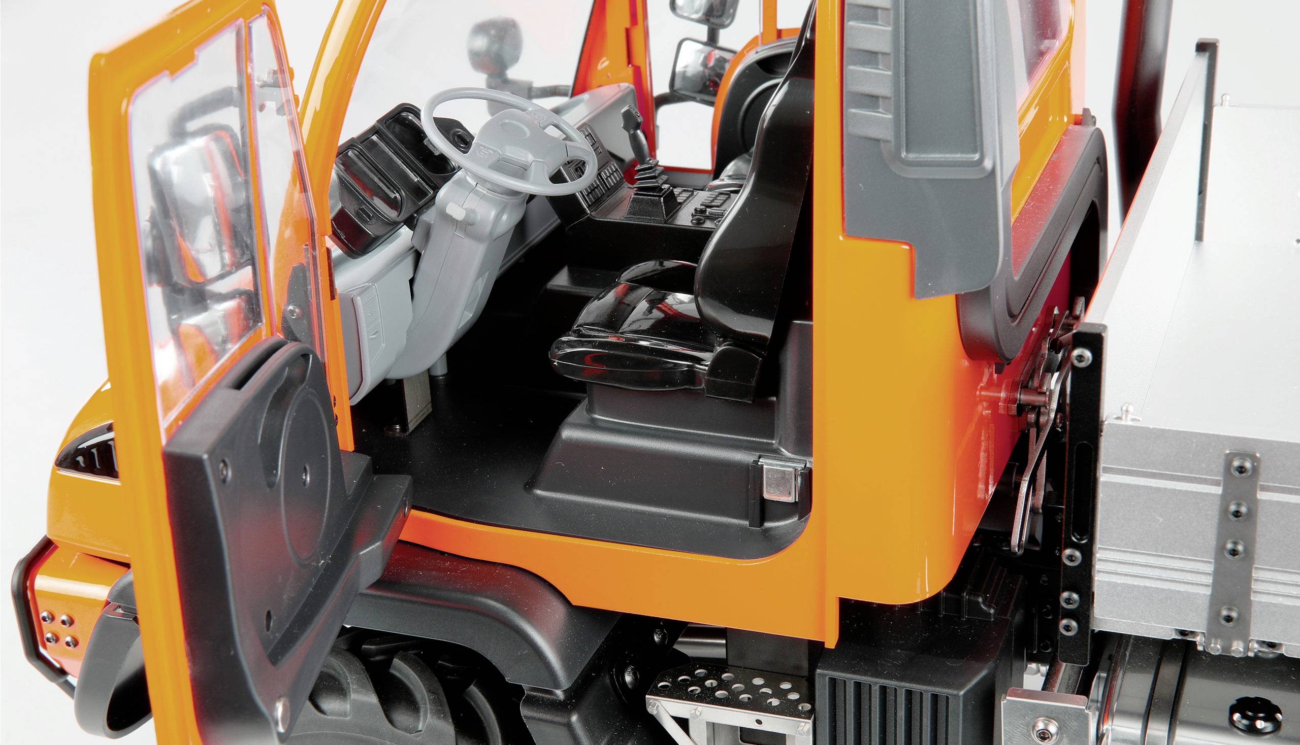 Interior of an orange lorry with the driver's door open. View of the steering wheel and driver's seat.