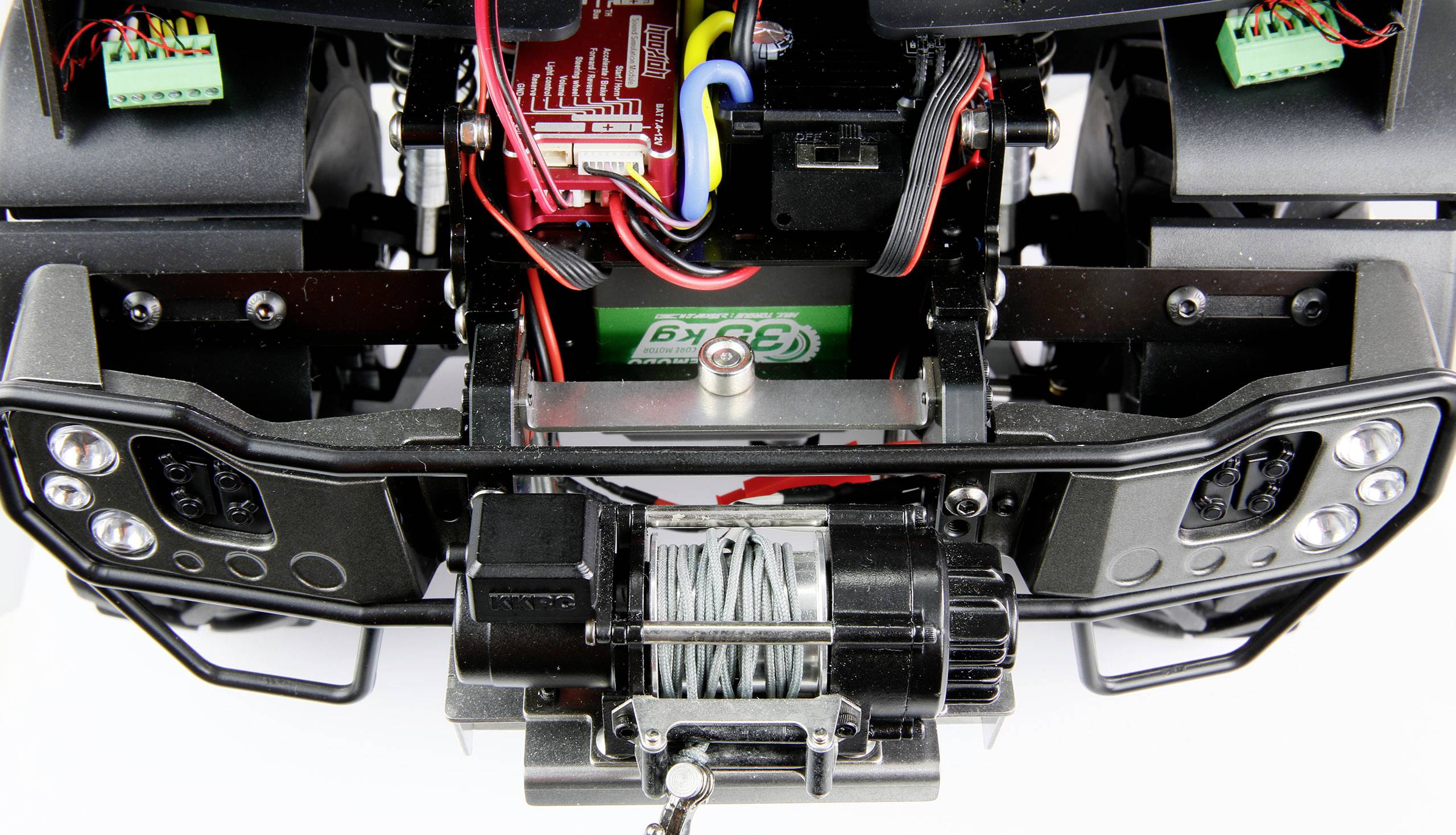 Close-up of a remote-controlled car chassis with visible winch cable and electronic components.
