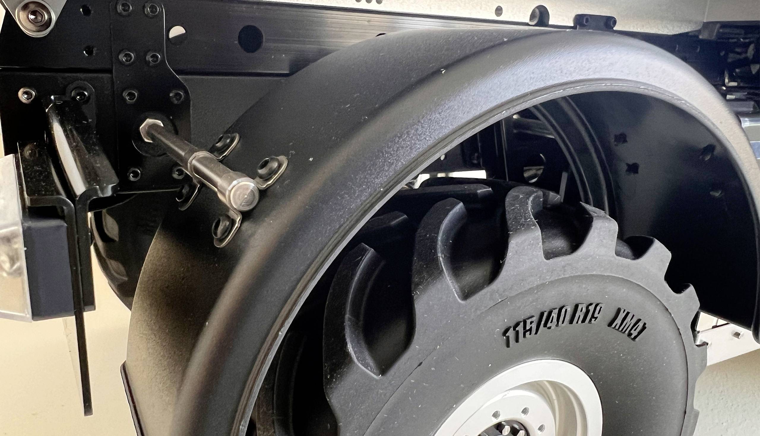 Close-up of a large black tyre of an agricultural vehicle with robust tread, secured to a metal frame.