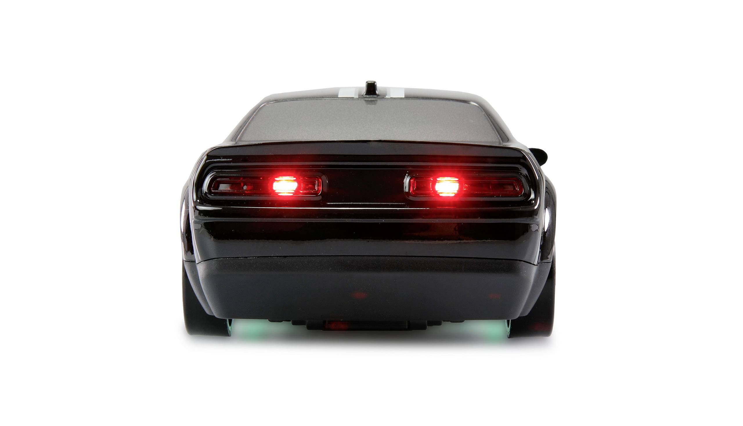 A black car from behind, showing illuminated red rear lights and green lighting underneath. It is stationary on a white background.