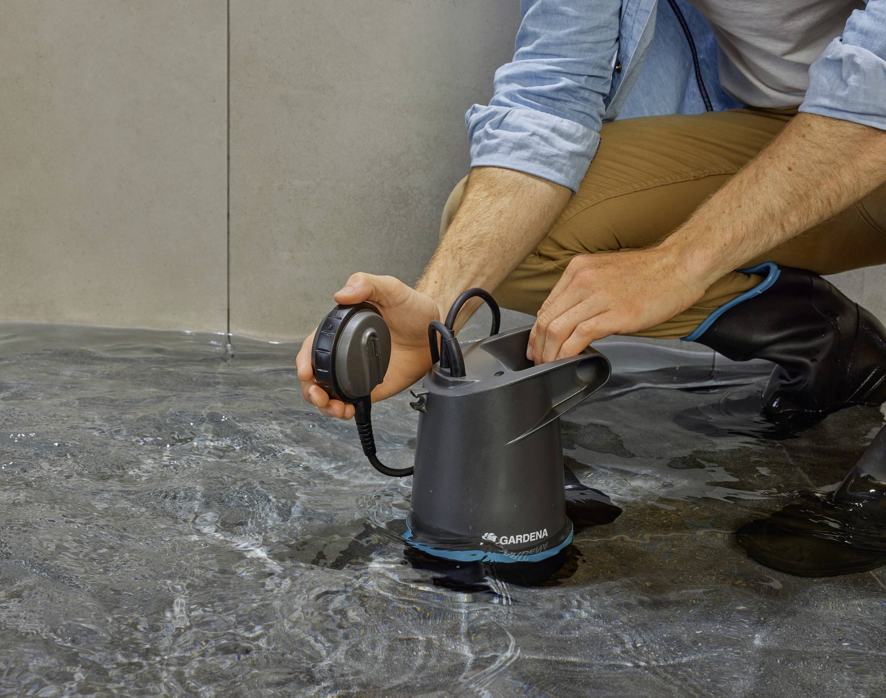 A person in wellington boots is testing a water pump in a flooded environment.