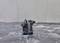 A black submersible pump stands in the water, surrounded by shallow waves and foam.