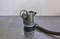 A black submersible pump with a blue ring and attached hose is standing on a wet grey floor.