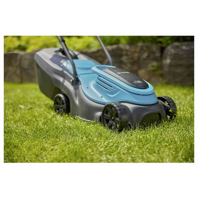 A blue and black lawn mower on green grass, with a stone wall in the background, suggesting a garden or yard setting.
