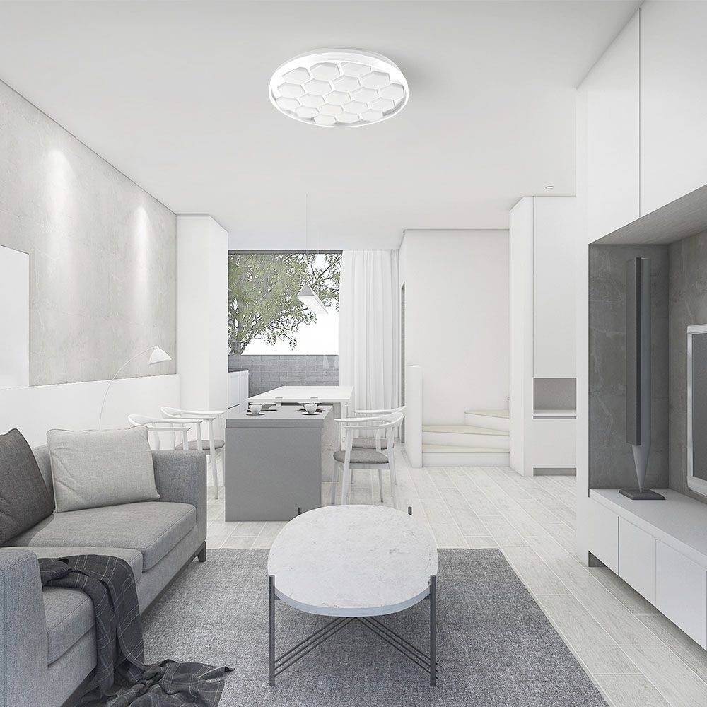 Bright modern living room with a grey sofa, round marble coffee table and view into a dining area. Large windows allow plenty of natural light to flood in.